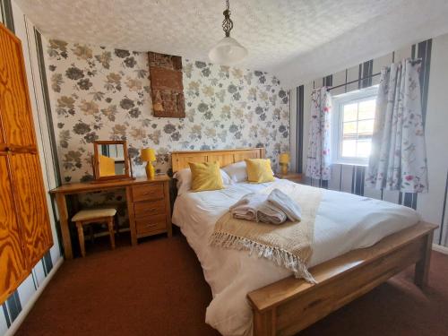 Schlafzimmer mit einem Bett, einem Schreibtisch und einem Spiegel in der Unterkunft Garth at Wetheral Cottages in Great Salkeld