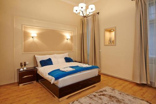 Un dormitorio con una cama con sábanas azules y una lámpara de araña. en Budapest Luxury Apartments, en Budapest