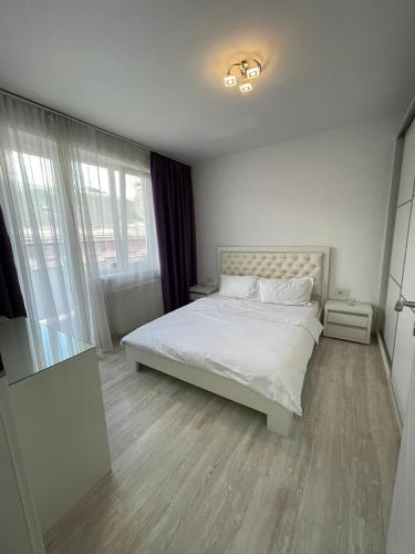 a bedroom with a white bed in a room with windows at CENTRAL VIEW APARTAMENT in Arad