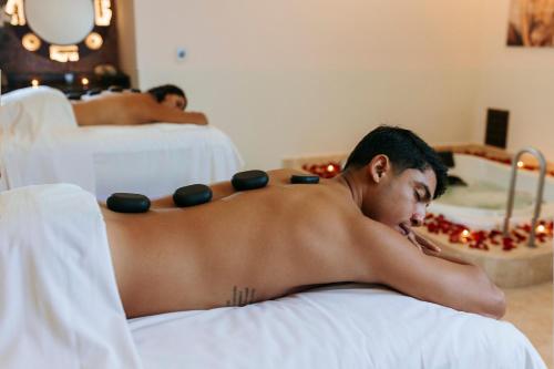 a shirtless man laying on a bed with weights on his back at Azul Ixtapa Grand All Inclusive Suites - Spa & Convention Center in Ixtapa