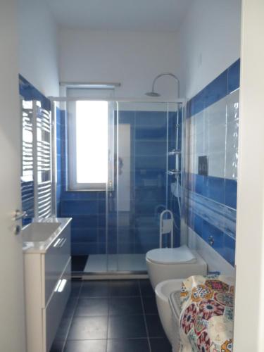 a blue bathroom with a toilet and a sink at Marea in Messina