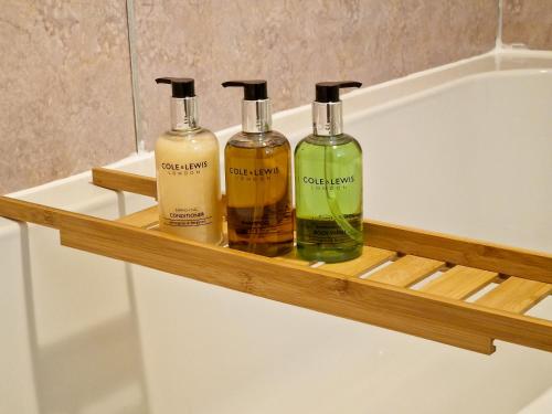 three bottles of soap on a wooden shelf in a bathroom at Windale at Wetheral Cottages in Great Salkeld