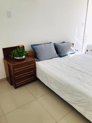 a bed with blue pillows and a table with a plant on it at Apartamento Praia de Porto Belo, Balneario Pereque, SC in Porto Belo