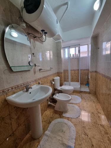 y baño con 2 aseos, lavamanos y espejo. en Solaris Guest House, en Shkodër