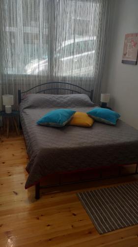 uma cama com almofadas azuis e amarelas num quarto em Penelope's and John's House em Kavala