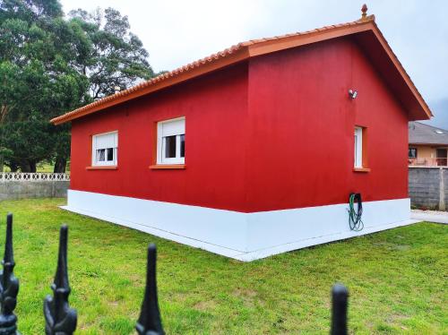 una casa roja en un patio con una valla en Ortegal Beach & Seacliffs, en Cariño