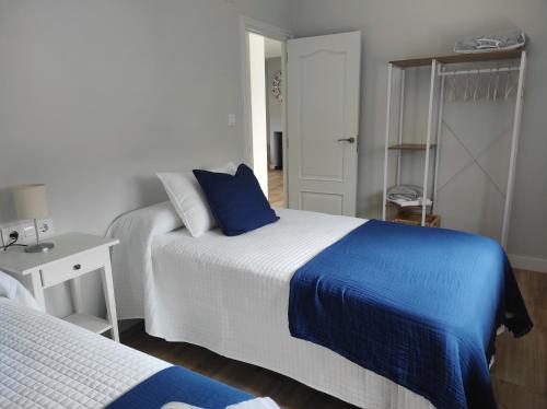 a bedroom with two beds with blue and white sheets at Ortegal Beach & Seacliffs in Cariño