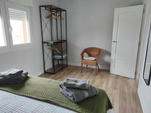 a bedroom with a bed with a green blanket and a chair at Ortegal Beach & Seacliffs in Cariño
