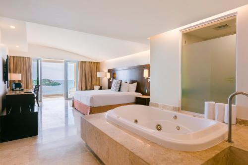 a hotel room with a bed and a bath tub at Azul Ixtapa Grand All Inclusive Suites - Spa & Convention Center in Ixtapa