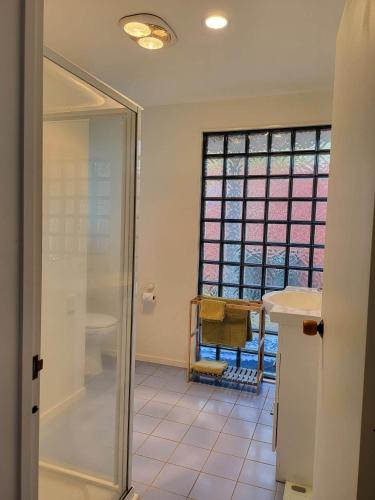 a bathroom with a shower and a glass door at Oceanside Haven in Ohope Beach