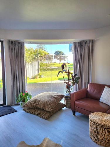 1 dormitorio con cama, sofá y ventana en Oceanside Haven en Ohope Beach
