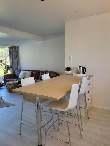 a dining table and chairs in a living room at Oceanside Haven in Ohope Beach