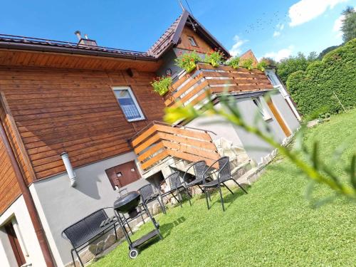an external view of a house with chairs and a patio at Lochówka - zaciszny domek w górach in Krynica Zdrój