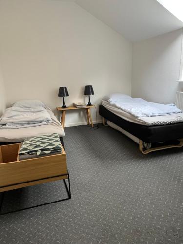 two twin beds in a room with two tables at Skøn centralt beliggende lejlighed m.tagterrasse in Herning