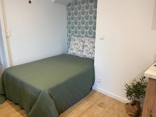 ein kleines Schlafzimmer mit einem grünen Bett in einem Zimmer in der Unterkunft Charmant studio in Bastia