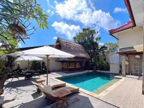 kuta 5BR private villa pool ,near airport, في كوتا: مسبح مع كراسي ومظلة بجوار منزل