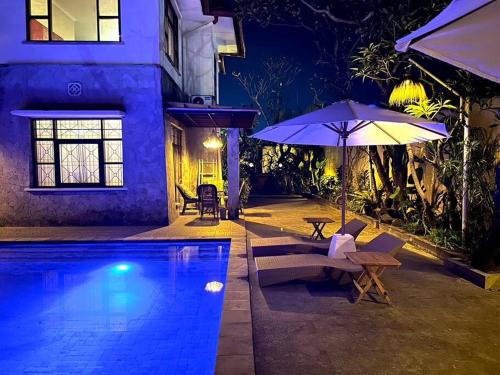 a house with a swimming pool and an umbrella at kuta 5BR private villa pool ,near airport, in Kuta