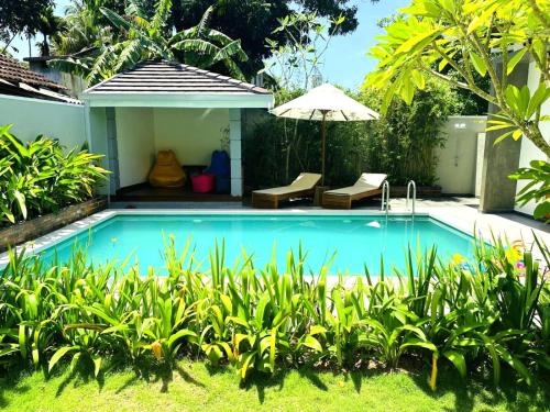 - une piscine dans un jardin avec un parasol dans l'établissement Moana La Vie - Polhena, à Matara