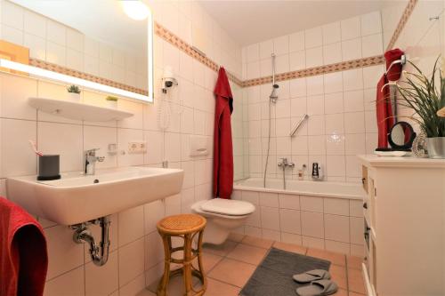 a bathroom with a sink and a toilet and a tub at Oewern Diek App 55 in Wustrow