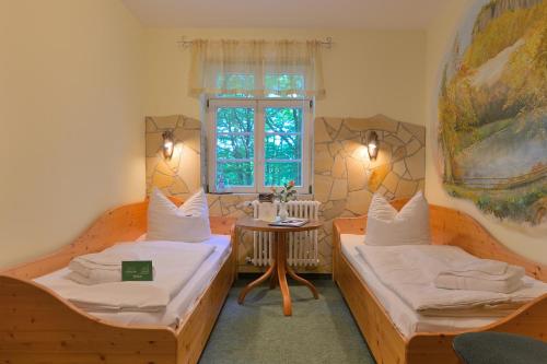 2 Betten in einem Zimmer mit einem Tisch und einem Fenster in der Unterkunft Gasthof Ungerberg in Neustadt in Sachsen