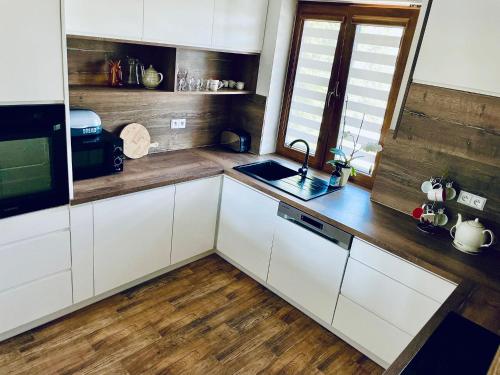a kitchen with white cabinets and a sink at Green Hill House in Pępice
