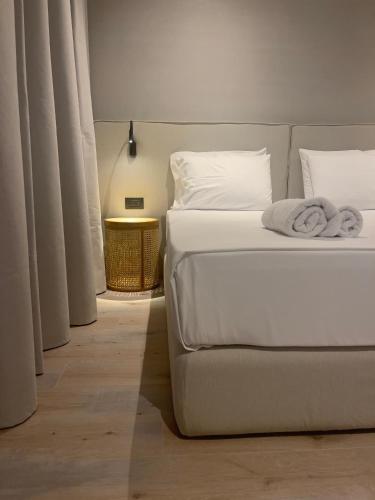 a bedroom with a bed with white sheets and a table at Andon Lapa Hotel & Spa in Sarandë