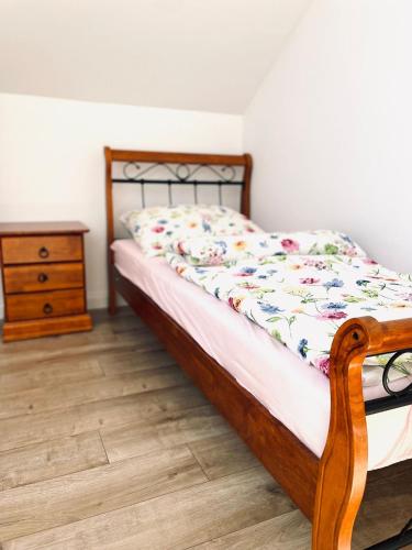 a bedroom with a bed with a wooden frame and a dresser at Green Hill House in Pępice