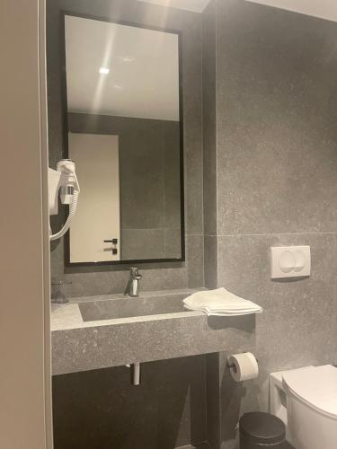 a bathroom with a sink and a mirror and a toilet at Andon Lapa Hotel & Spa in Sarandë