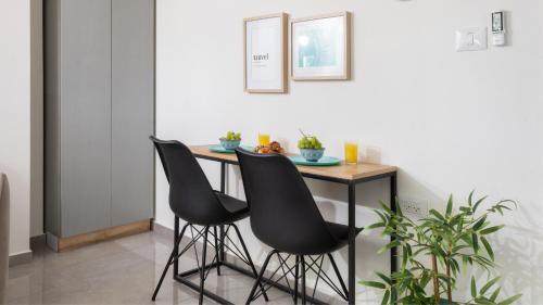 una mesa con 2 sillas negras en una habitación en אורה דירות אירוח - הנופש האיכותי ביותר למשפחות, מגוון דירות, en Eilat