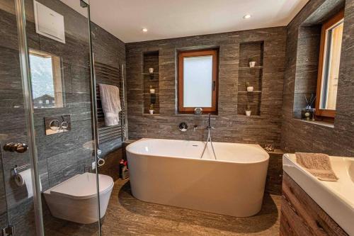 a bathroom with a tub and a shower and a toilet at Sonnhalde II - Luxury Chalet in Saas-Fee