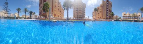 a large blue swimming pool in front of buildings at La Manga del Mar Menor Los Miradores block 1 5th floor G in Murcia