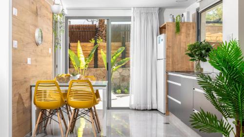 a kitchen with yellow chairs and a table in a kitchen at By Eezy - אורה דירות אירוח in Eilat