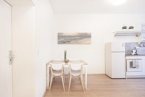 a white kitchen with a table and two chairs at DO One Bedroom Flat in Dortmund