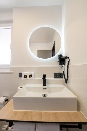 a bathroom with a white sink and a mirror at V Business Apartments Böblingen in Böblingen