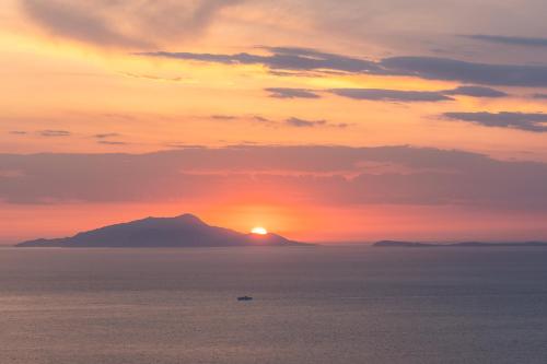 a sunset over the ocean with a boat in the water at Al Calar del Sole in Massa Lubrense