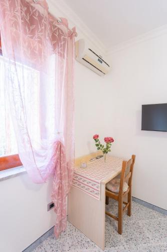 a room with a table and a window with a pink curtain at Al Calar del Sole in Massa Lubrense