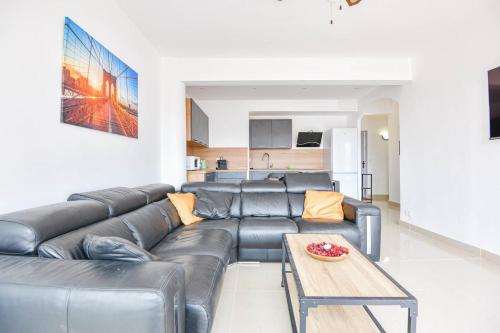 ein Wohnzimmer mit einem Ledersofa und einem Tisch in der Unterkunft La Canebière - Appart 2 chambres avec terrasse in Marseille