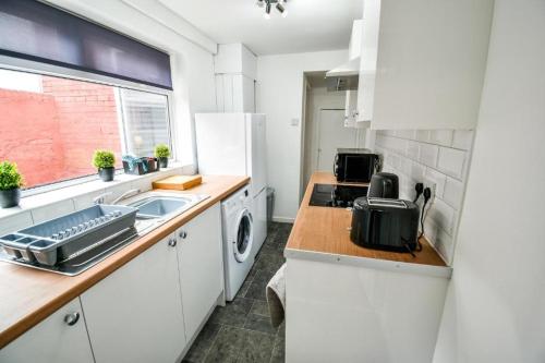 een witte keuken met een spoelbak en een magnetron bij Lister House in Hartlepool
