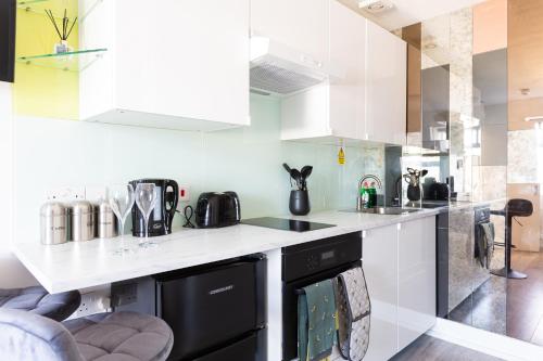 a kitchen with white cabinets and a black dishwasher at Cozy and Small Studio Zone 2 near Maida vale 6 in London