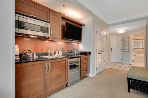 a kitchen with wooden cabinets and a sink and a tv at Premium Suite MGM Signature HIGH FLR Balcony Strip View in Las Vegas