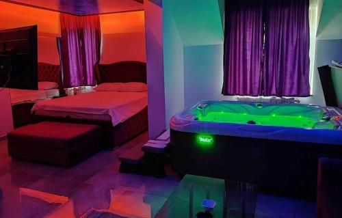 a room with a tub and a bedroom with a bed and a table at Hedonic Wellness Apartmani in Niš
