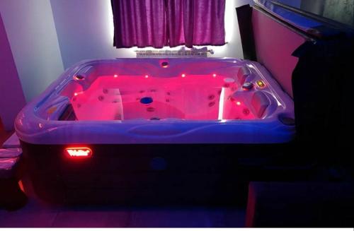 a hot tub with red lights in a room at Hedonic Wellness Apartmani in Niš