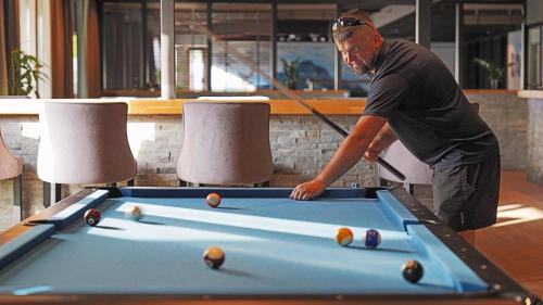 a man standing over a pool table with a cue at Bremanger Fjord Hotell in Svelgen