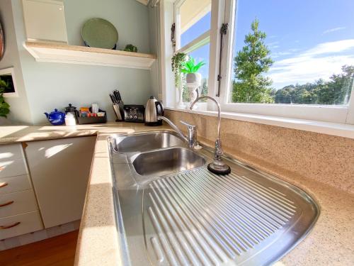 fregadero de acero inoxidable en una cocina con ventana en Kauri Villas en Parua Bay