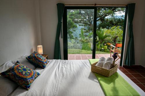 a bedroom with a bed and a large window at Ecohotel Monteverde in La Vega