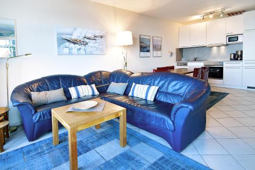 sala de estar con sofá de cuero azul y mesa en Haus-am-Kliff-App-07, en Heringsdorf
