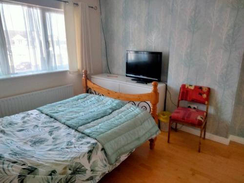 a bedroom with a bed and a tv and a chair at 19 Doran Close in Donegal