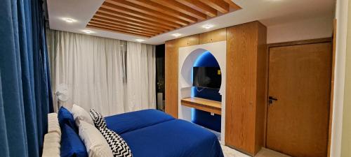 ein Schlafzimmer mit einem blauen Bett und einem TV in der Unterkunft RABAT RESIDENCE - rooms in Rabat