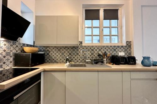 a kitchen with white cabinets and a sink at Rive Droite - Studio Trouville in Trouville-sur-Mer