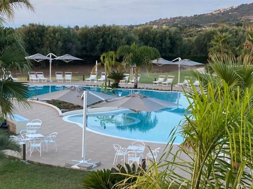 una piscina con sillas y sombrillas en un complejo en Agave Blu, en San Nicolò